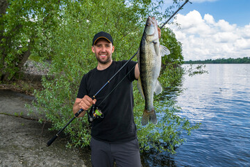 Successful zander fishing. Happy fisherman with big walleye fish trophy at lake