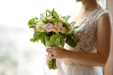 Bride holding stylish wedding flowers. Elegance rustic style pastel colors bouquet in woman hands