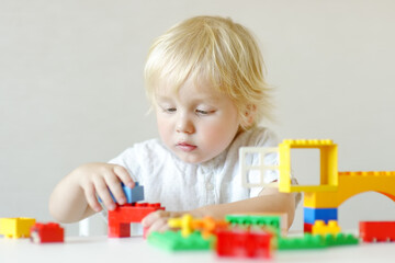 Little child playing with colorful plastic blocks at kindergarten or home. Educational toys for preschooler children. Development through the game.