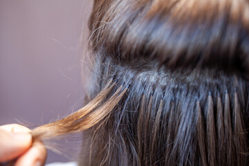 Bundles of hair extensions on a woman's head. Hair extensions to thicken your own. Individual strands of hair close-up