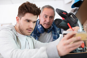 student and teacher in carpentry class using circular saw