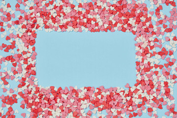 Valentine day greeting card or banner. Frame of candies hearts of pastel colors on blue paper or background. Top view. 