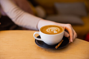 cropped view of young woman near cup of cappuccino.