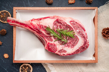 Fresh Tomahawk beef steak with rosemary on wooden plate, Tomahawk beef steak on black wooden...