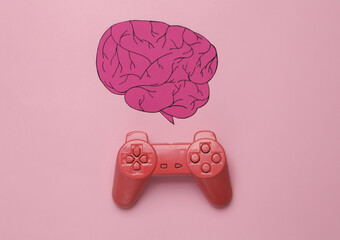 Paper-cut brain and gamepad on a pink background. The impact of games on the human brain