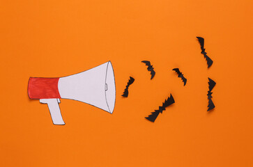 Paper cut cartoon megaphone with bats on orange background. Halloween concept
