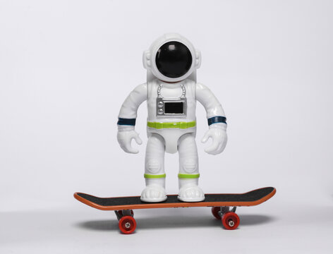 Astronaut toy model ride on skateboard isolated on white background