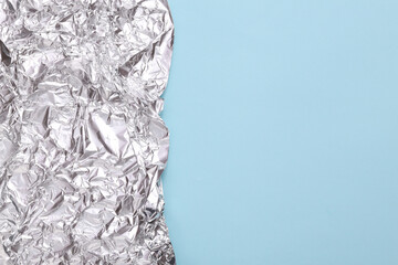 Fototapeta na wymiar Crumpled metal foil on blue background with copy space