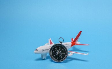 Travel, voyage concept. Model of a passenger plane with compass on blue background