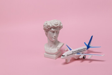 Travel, tourism or voyage concept. Model of a passenger plane with David bust on pink background