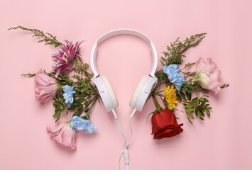 Music day concept.Stereo headphones with flowers on a pink background. Romantic music. Flat lay, top view