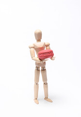 Wooden puppet holding french macaroon isolated on white background