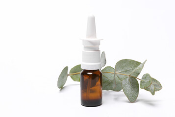 Treatment of runny nose and colds. Nasal spray bottle with eucalyptus sprig isolated on white...