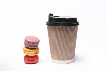 Cardboard coffee cup with stack of french macaroons isolated on white background