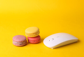 Pc mouse with French macaroons on a yellow background. Online restaurant