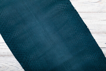 blue dyed folded natural genuine python leather on the wooden table	
