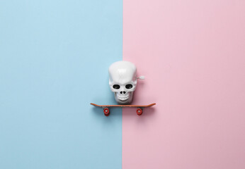 Skull on a skateboard on a blue-pink pastel background. Minimal halloween still life - obrazy, fototapety, plakaty