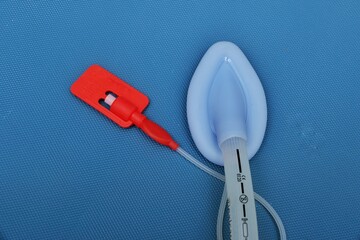 Inserting tip of a adult laryngeal mask airway (LMA). Image isolated on blue background.