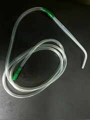 A Yankauer suction set with suction tubing placed on a dark background