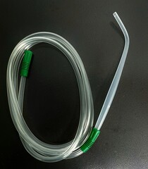 A Yankauer suction set with suction tubing placed on a dark background.