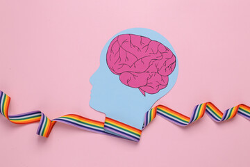 Paper cut human head with brain and lgbt rainbow ribbon on pink background