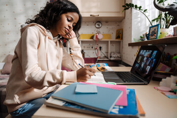 African teen girl sitting with laptop propping her head