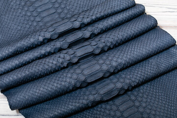 blue grey dyed genuine natural python leather on the wooden table	