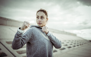 Sporty woman fighter stands in a fighting stance outdoors