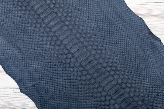 blue grey dyed genuine natural python leather on the wooden table	