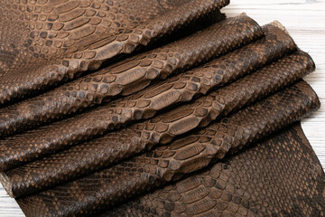 Brown dyed folded natural genuine python leather on the wooden table	