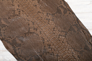 Brown dyed folded natural genuine python leather on the wooden table	