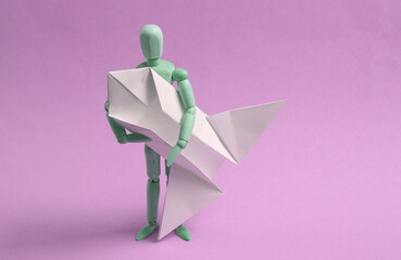 Wooden puppet with origami space shuttle on purple background. Startup, Dreamer, Spaceflight Concept