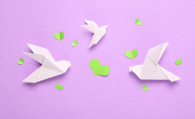 Origami doves with hearts on pastel background. Top view