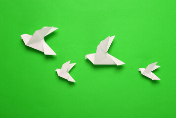 Origami pigeons on green background