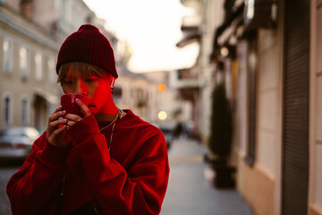 Asian boy listening music with earphones while drinking coffee