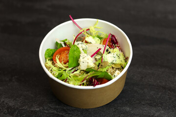 Healthy salad with beetroot, blue cheese, tomatoes, quinoa and pumpkin seeds in eco paper package for take away or food delivery isolated on black background. Top view. Keto diet.