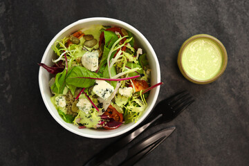 Healthy salad with beetroot, blue cheese, tomatoes, quinoa and pumpkin seeds in eco paper package for take away or food delivery isolated on black background. Top view. Keto diet.