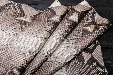 grey spotted dyed folded natural genuine python leather on the wooden table	
