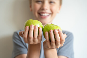 Smiling сhild held forward green apples in his hands over white background. Delicious and healthy...