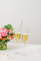 flowers behind two full champagne glasses