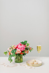 pink and peach flowers and vanilla macarons with glass of champagne