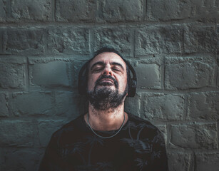 Man leaning against a concrete wall while listening to music