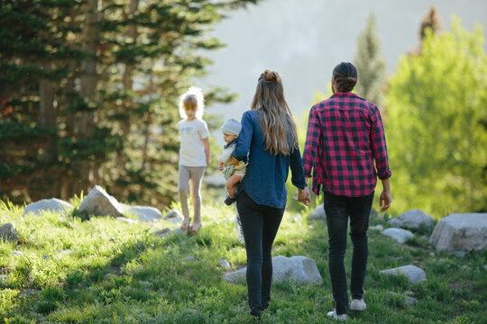Family holding hands walking in the woods together in Utah mountains