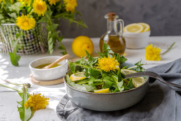 Dandelion salad with olive oil, lemon juice and spices on white wooden table with grey background - obrazy, fototapety, plakaty
