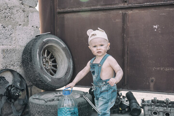 one year old baby playing mechanic among auto parts