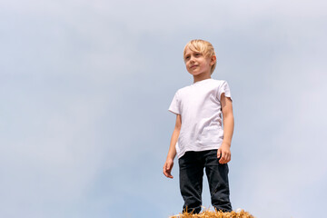 Fair-haired boy teenager in white T-shirt on blue sky background. Summer vacation. Bottom view © somemeans