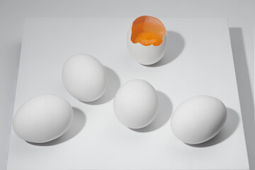 White whole eggs and broken egg with a yolk on a white background. Composition of cracked egg with...