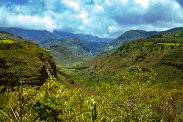 Stormy clouds over the beginnings of Waimea Canyon on the Hawaiian Island of Kauai with green jungle plants and deep mountain canyon