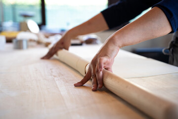 Close up of female hands working with rolling-pin for italian fresh pasta -  Female hands rolling  for fresh dough on the wooden table - concept of cooking and fresh homemade pasta