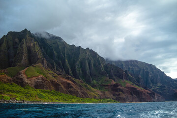 The gorgeous rugged wilderness and cliffs of Kauai's Napali Coast in Hawaii, with low clouds and...